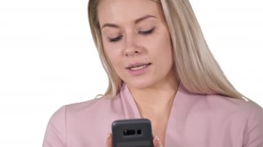O beyaz arka plan üzerinde bir kısa mesaj türleri gibi gülümsediğini cep telefonu kullanan trendy gülümseyen sarışın kadın.