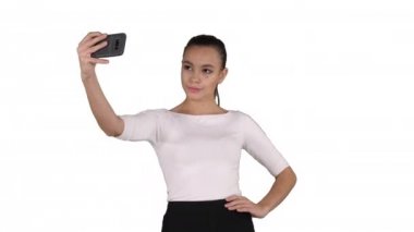 Beyaz arka plan üzerinde yürürken bir selfie alarak gülümseyen çekici kadın.