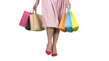 Genç kadın bacaklar beyaz arka plan üzerinde taşıma renkli alışveriş torbaları.