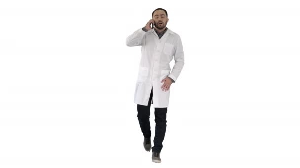 Мужчина врач ходить и говорить по телефону на белом фоне. — стоковое видео