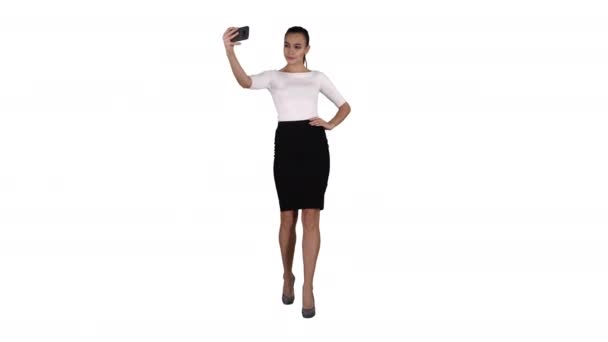Χαμογελώντας ελκυστική γυναίκα να βγάζει μια selfie ενώ το περπάτημα σε λευκό φόντο. — Αρχείο Βίντεο