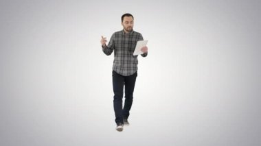 Tabletle gelişigüzel yürüyen ve gradyan arkaplan üzerine video konferansı yoluyla konuşan adam.