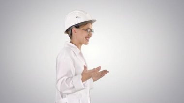 Laboratuvar önlüğü ve yürüyüş ve bir degrade arka plan üzerinde anlamı hardhat genç bilim adamı.