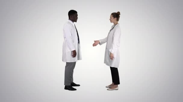 Eğilimli arka planda el sıkışan iki genç doktor. — Stok video