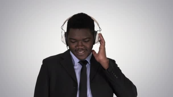 Knappe Afro-Amerikaans zakenman in hoofdtelefoon luistert naar muziek op de achtergrond met kleurovergang. — Stockvideo