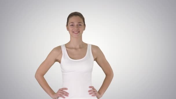 Satisfait confiant actif femme en bonne santé dans les vêtements de sport avec les mains sur les hanches marchant sur fond dégradé . — Video