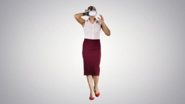 Yürüyen genç kadın, gradyan arka planda vr gözlüğü kullanıyor.