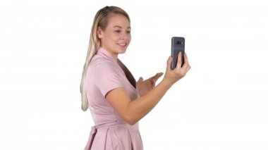 Kadın pembe elbiseli beyaz arka plan üzerinde akıllı telefonu ile video arama yapma.