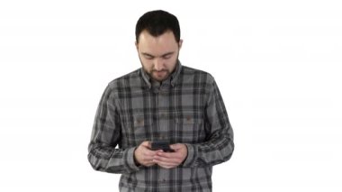 Genç adam yürüyor ve beyaz arka planda akıllı telefon kullanıyor..