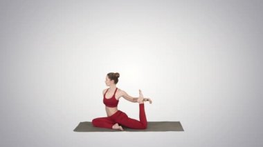 Tek bacaklı Kral güvercin poz, Eka Pada Rajakapotasana degrade arka plan üzerinde yoga ya da pilates egzersiz yaparak kırmızı spor giyim giymiş güzel genç kadın.