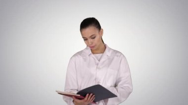 Genç kadın degrade arka plan üzerinde yürürken belgeleri okuma doktor.