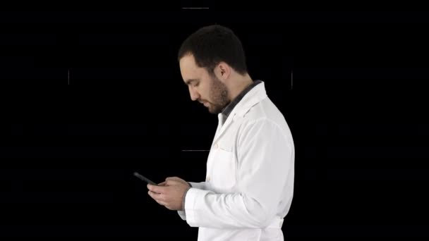 Walking doctor or nurse texting on a cell phone, Alpha Channel — Stock Video