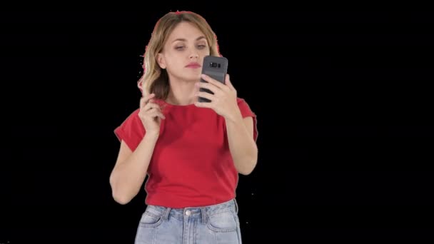 Eine nette junge Frau glättet ihre Haare und schaut ins Handy, Alpha Channel — Stockvideo
