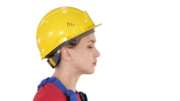 Młoda kobieta inżynier z żółtym kask chodzenia i uśmiecha się na białym tle. — Wideo stockowe