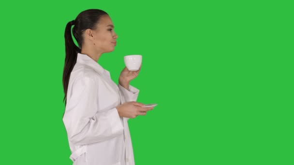 Junge Krankenschwester entspannt Kaffee oder Tee trinken, während sie auf einem grünen Bildschirm läuft, Chroma-Schlüssel. — Stockvideo
