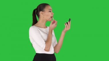 Güzel kadın, boya maddeler, Araçlar onun dudaklarına ruj pembe, yeşil ekranda, Chroma Key aynaya bakıyor.