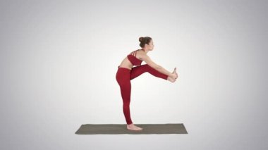 Güzel genç kadın spor spor egzersiz yaparak Utthita Hasta Padangusthasana, Dandayamana-Janushirasana degrade arka plan üzerinde varyasyon bükme yerleştirmek.