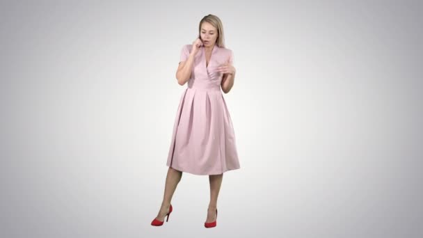Beautiful woman in pink speaking over phone having a serious talk on gradient background. — Stock Video