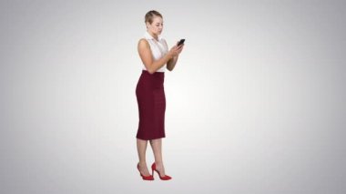 Genç bir bayan telefonuyla gradyan arkaplana bakıyor..