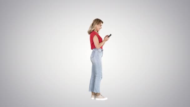 Nenucená mladá žena psaní na mobilním telefonu na pozadí gradient. — Stock video