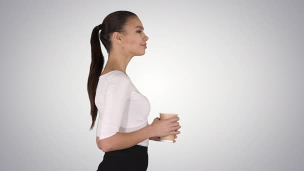 Ontspannen stijlvolle zakenvrouw drinken koffie lopen op gradiënt achtergrond. — Stockvideo