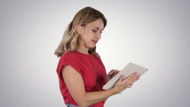 Mujer con camiseta roja usando tableta sobre fondo degradado. — Vídeos de Stock