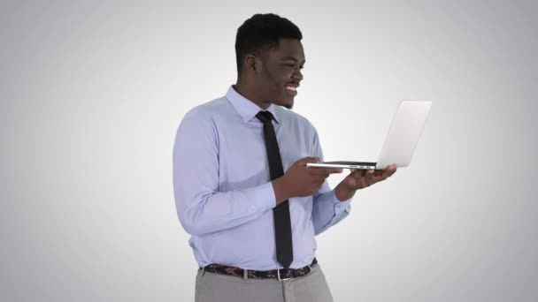 Веселый успешный молодой афроамериканский менеджер с ноутбуком проводит видеоконференцию с деловыми партнерами на градиентном фоне. — стоковое видео