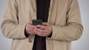 Trençkot mobil akıllı telefon üzerinde gradyan arka planı kullanarak adam.