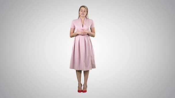 Szőke nő rózsaszín ruhában beszél kamera gradiens háttér. — Stock videók