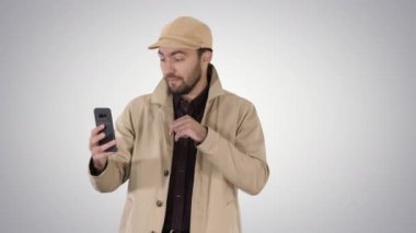 Genç adam gradyan arka planda yürürken cep telefonundan bir video görüşmesi yapıyor..
