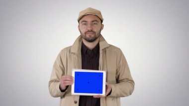 Yürüyüş ve tablet ile mavi ekran mockup degrade arka plan üzerinde tutan adam.