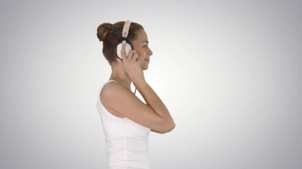 Щаслива випадкова дівчина в навушниках, що ходять на градієнтному фоні . — стокове відео