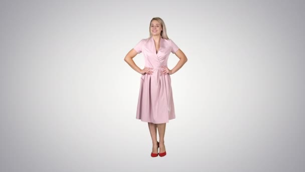 Woman in dress with hands on hips walking while looking at camera on gradient background. — Stock Video