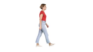 Kırmızı t-shirt, kot pantolon ve spor ayakkabı beyaz arka plan üzerinde yürüyen kadın.