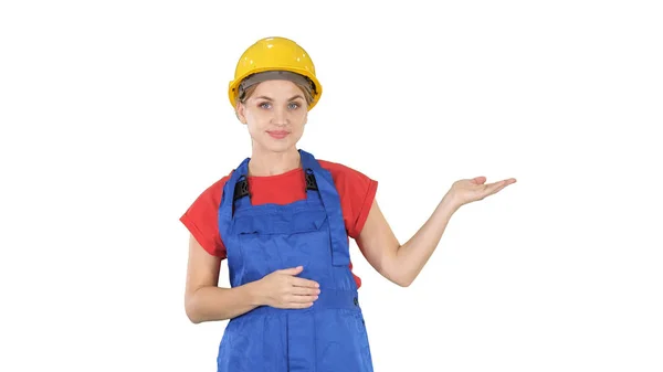 Young builder worker woman presenting showing product with her hands from her sides on white background. — Stock Photo, Image