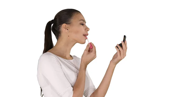 Mooie jonge vrouw zetten op lippenstift op witte achtergrond. — Stockfoto