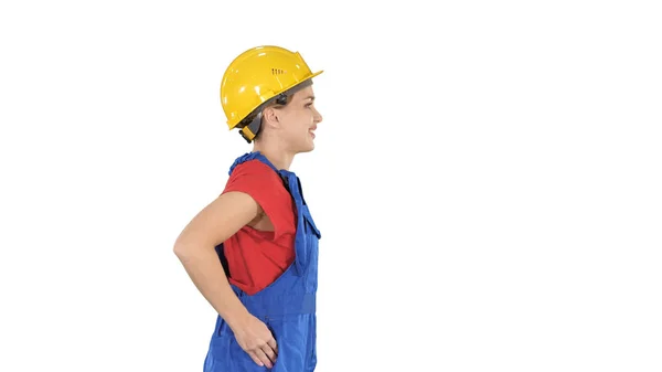 Mujer joven en hardhat amarillo caminando sobre fondo blanco. — Foto de Stock