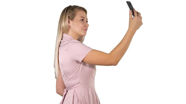 Junge schöne Frau macht Selfie auf ihrem Handy auf weißem Hintergrund. — Stockfoto