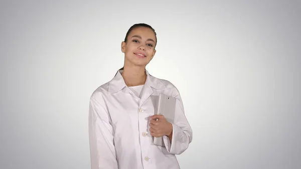 Vrouwelijke arts die met tablet in handen op een hellende achtergrond loopt. — Stockfoto