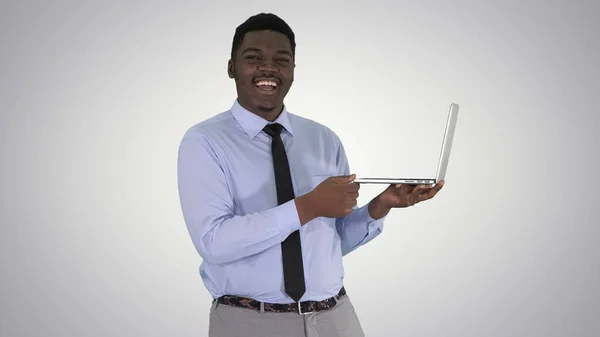 在梯度背景下与手持笔记本电脑的年轻非洲男子交谈. — 图库照片