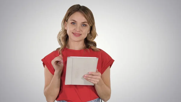 Smiling woman with tablet computer presenting turning pages on gradient background. — Stock Photo, Image