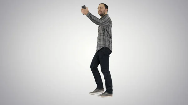 グラデーションの背景に selfie を作る若い男にひげを生やした幸せな笑みを浮かべて歩いてイケメン. — ストック写真
