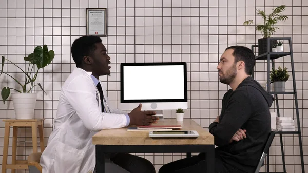 Ο γιατρός δείχνει ιατρικά αρχεία στον υπολογιστή του για να τον ασθενή του, αυτός δείχνει στην οθόνη. Λευκή οθόνη. — Φωτογραφία Αρχείου