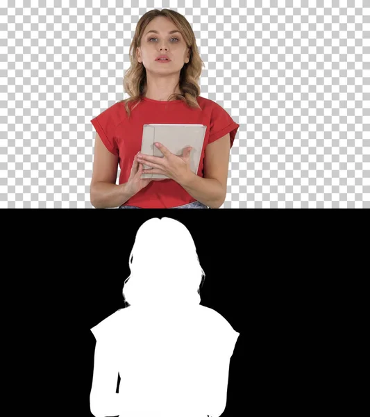 Dáma v červeném tričku drží v ruce tablet s vážným obličejem mluví s kamerou, Alpha Channel — Stock fotografie