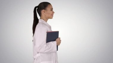 Mutlu gülümseyen kadın doktor Holding defter ve belgeler üzerinde gradyan arka planı yürüyüş.