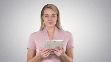 Güzel kadının sayfaları çevirme ve degrade arka plan kameraya bakarak tablet kullanarak orta atış.