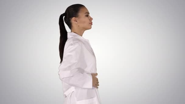 Jonge vrouw apotheker in witte jurk uniform lopen op gradiënt achtergrond. — Stockvideo