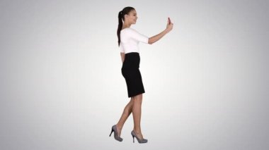Latin kökenli genç bir kadın video görüşmesi yapıyor ya da gradyan arkaplan üzerine video blogu kaydediyor.
