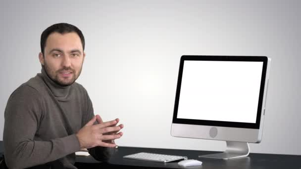 Casual hombre de negocios sonriendo y hablando a la cámara que muestra algo en el monitor de la computadora en el fondo gradiente . — Vídeo de stock