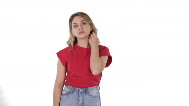 Mujer joven con el pelo rubio en camiseta roja mirando a la cámara sin emociones sobre fondo blanco . — Vídeos de Stock